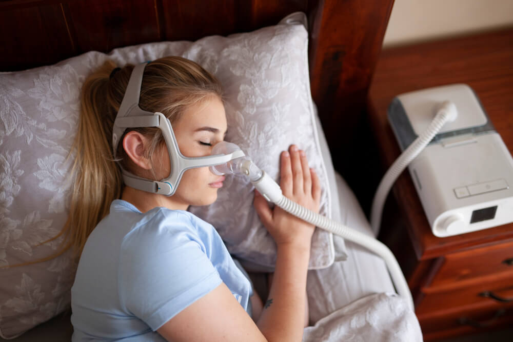 Young female sleeping with cpap machine for sleep apnea.