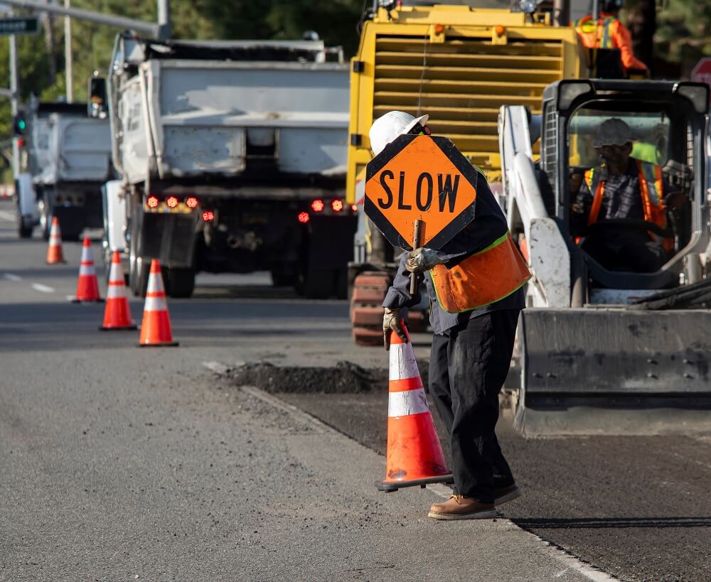 Highway construction worker putting warning signs.