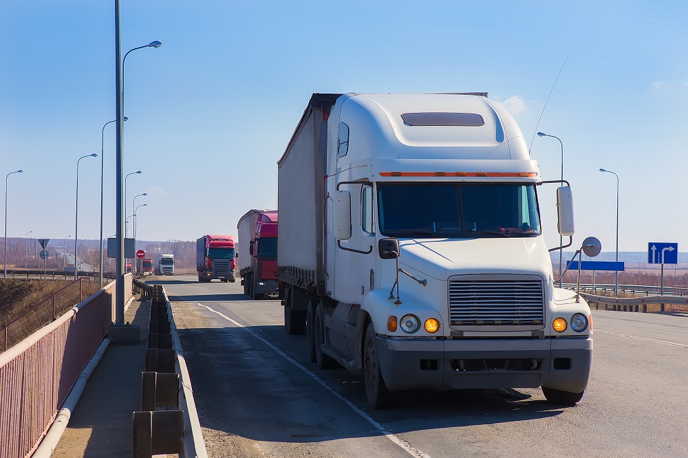 White semi-truck driving on the highway.