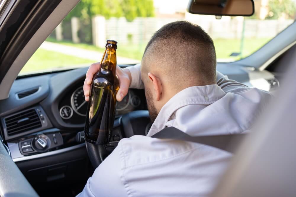 Man drinking alcohol while driving a car.